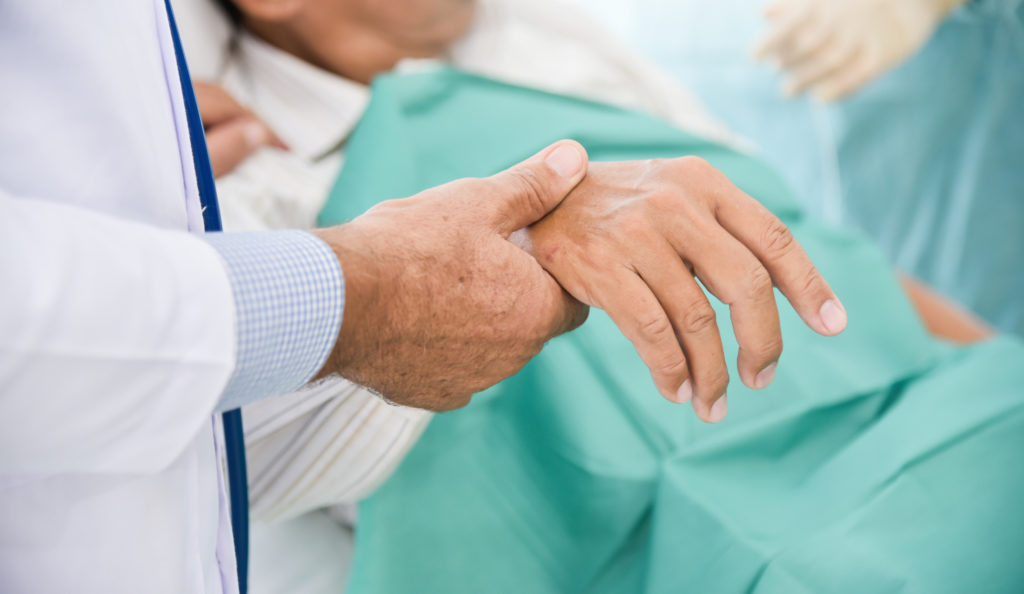 doctor holding hand of elderly resident at a nursing home that has a state-of-the-art ventilator care unit in Shreveport, LA
