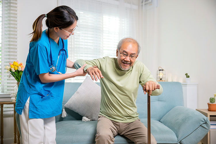 An SNF nurse helps an elderly man up from his chair in Shreveport, LA