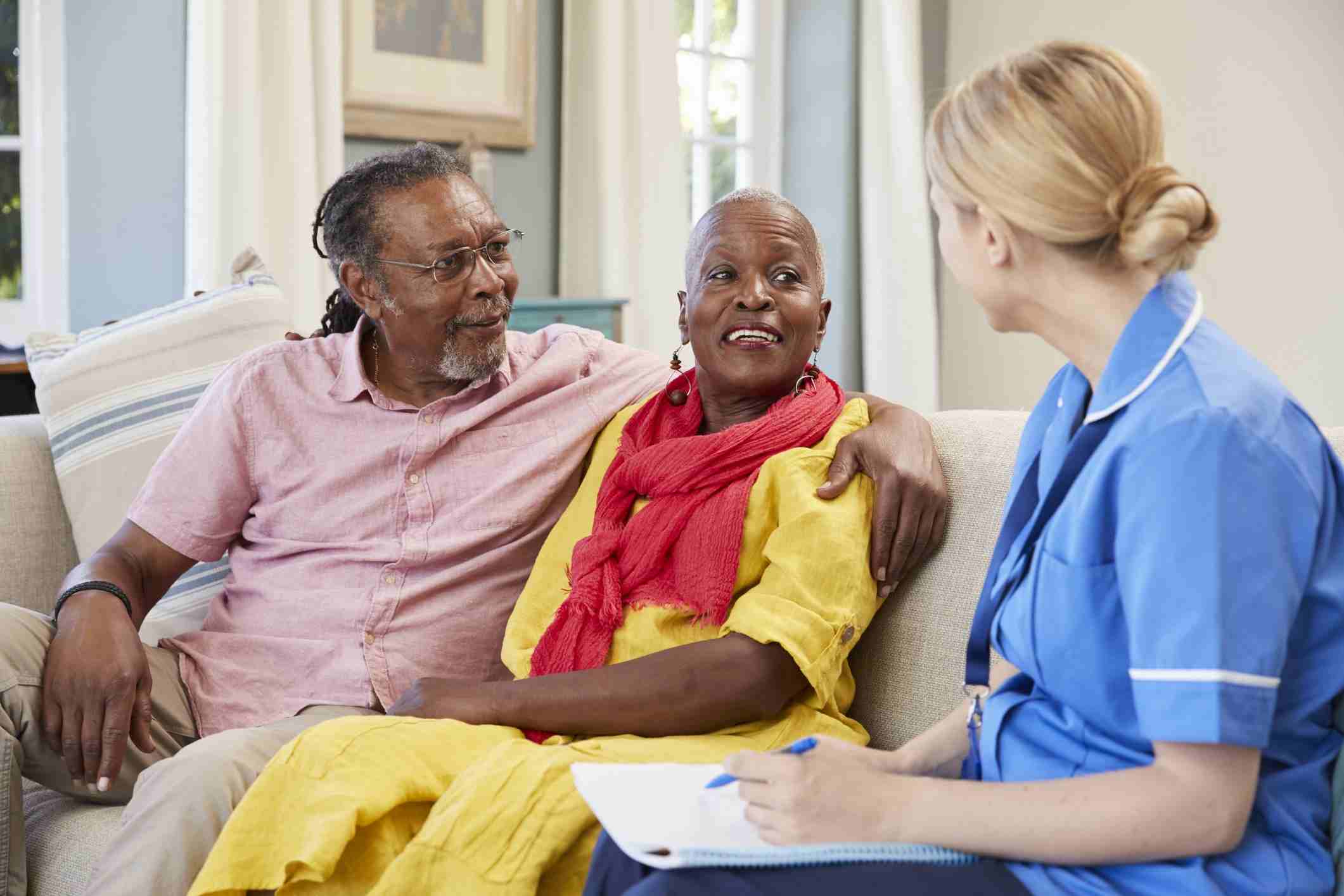 Nurse converses with an elderly couple on a couch in Shreveport, LA
