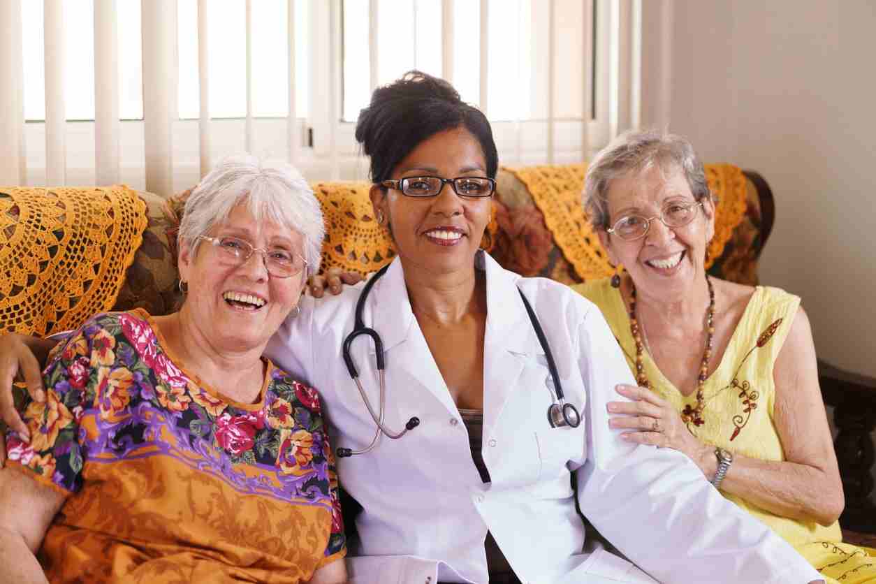 A woman with a stethoscope sits beside two older women, discussing health in Shreveport, LA