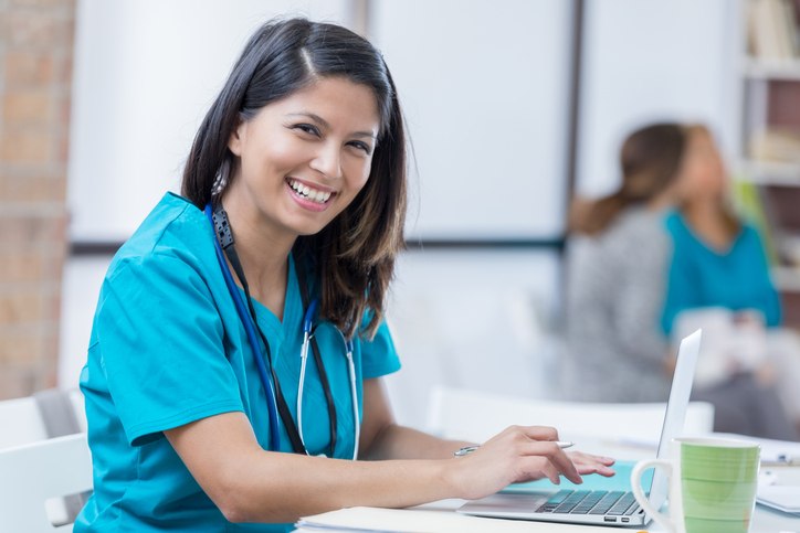 Nurse smiling while using her laptop, highlighting careers in nursing in Shreveport, LA