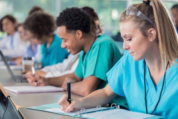 A group of nurses writes at a table, focusing on the Tuition Reimbursement Program in Shreveport, LA
