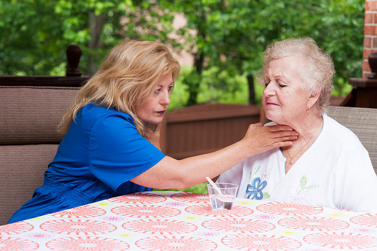 A woman assists an older woman with neck support during Speech Therapy Services in Shreveport, LA