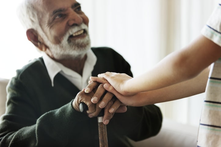Elderly man with cane smiling at young boy