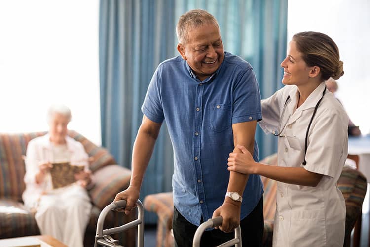 Nurse assists elderly man walking in skilled nursing facility