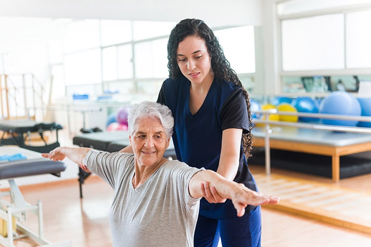 Physical therapist helps senior woman stretch her arms 1