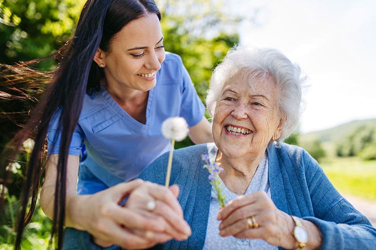 Smiling senior woman outside with nurse providing respite care